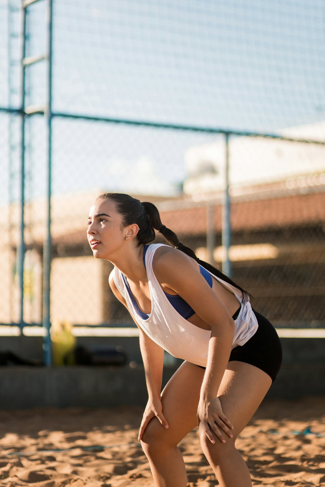 a woman in a white shirt and black shorts playing a game of volleyball